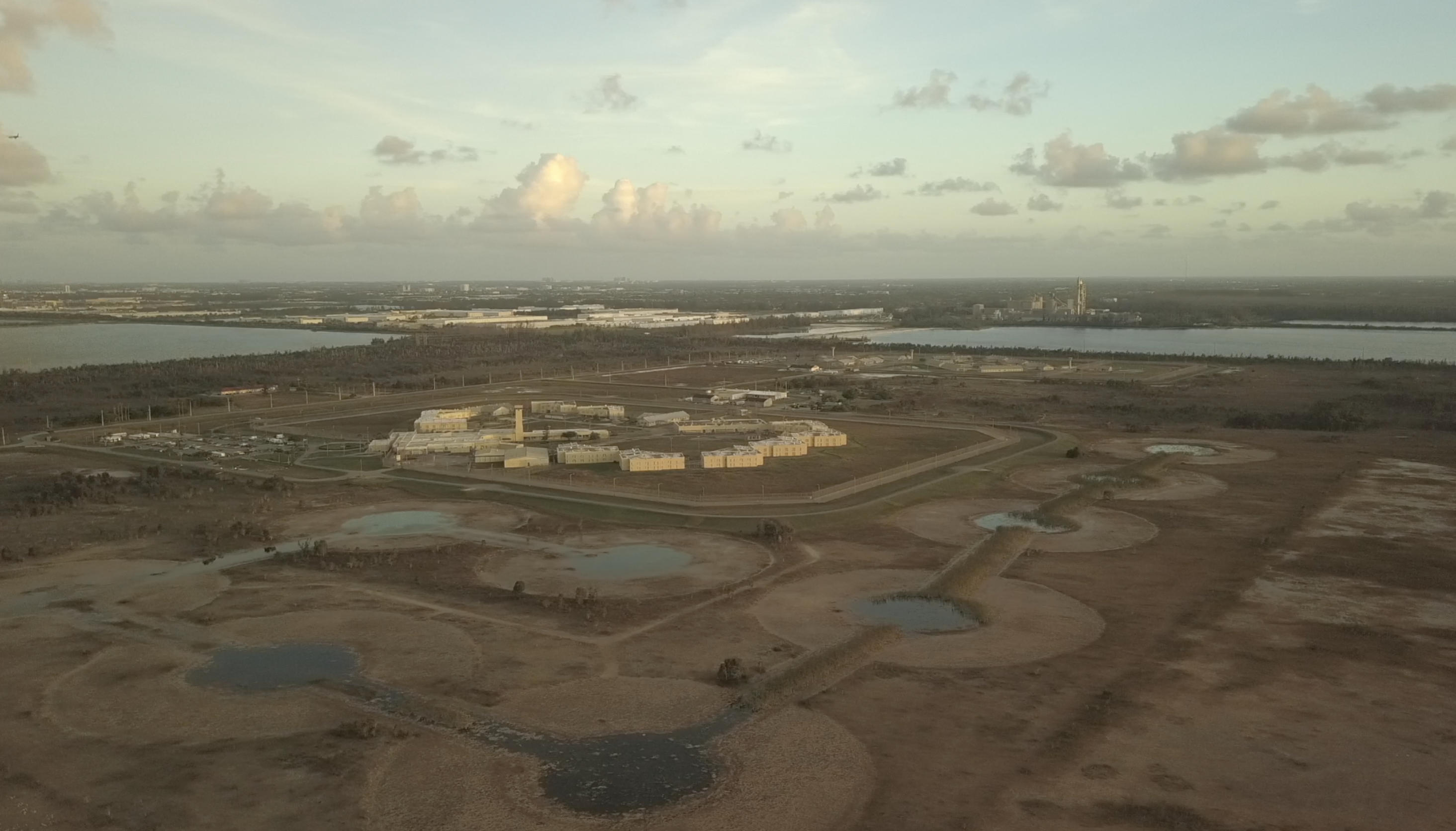 aerial view of a prison surrounded by an engineered wetland, with limestone quarries in the background