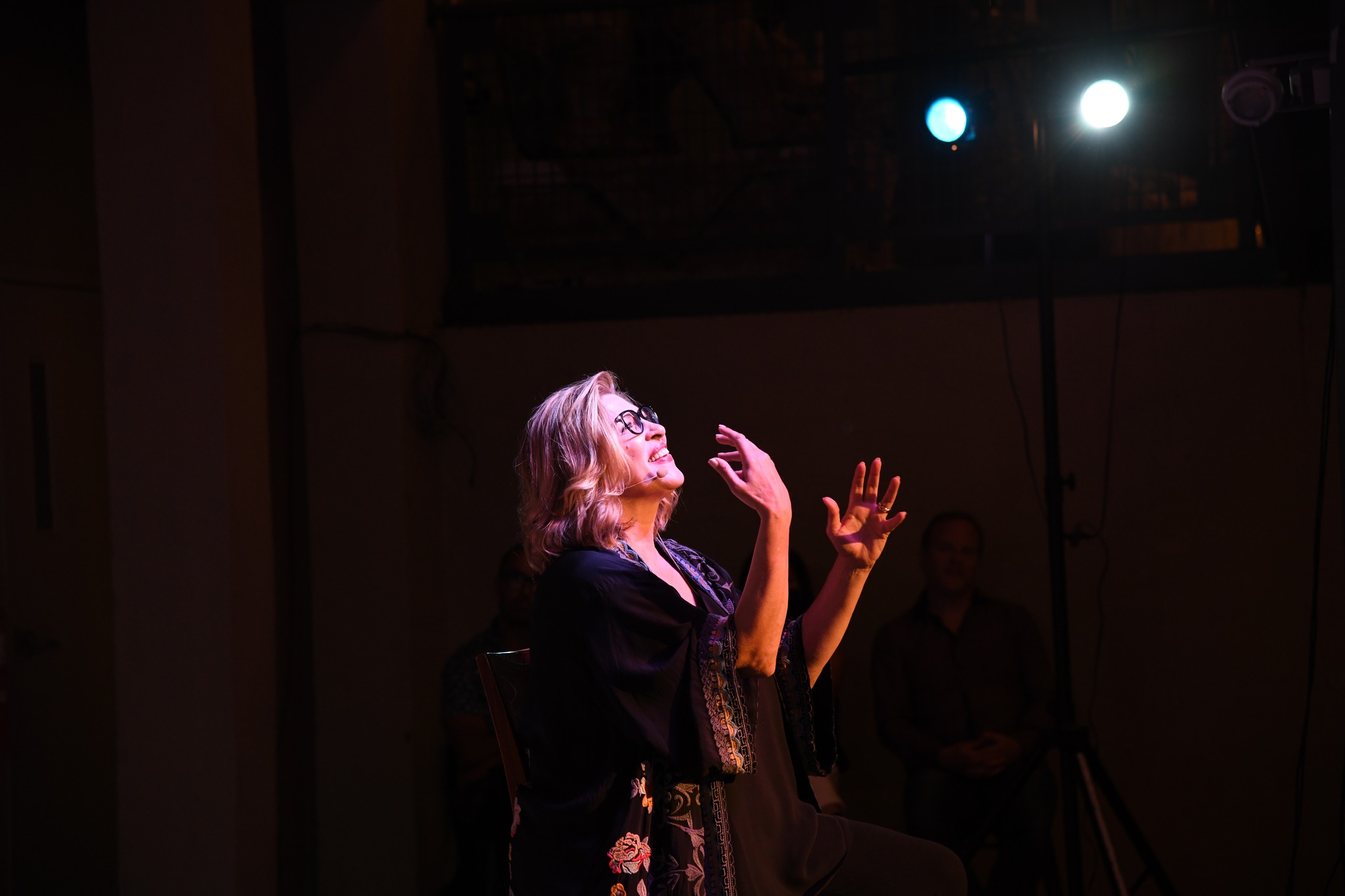 Woman standing in stage light using sign language