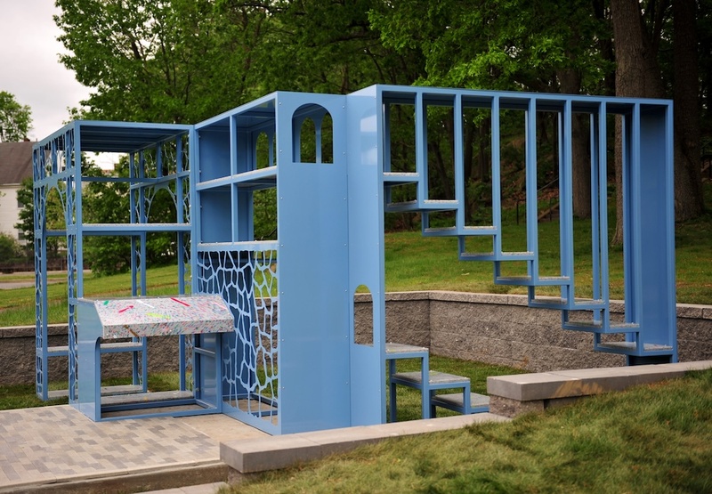  A blue iron sculpture sits outside on a concrete floor. 