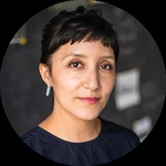 A headshot of a Latinx woman with long dark hair tied in a bun.