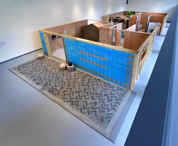  An installation of a blue building with red interior. The building has no roof and is made inside as part of an art installation. 
