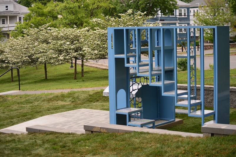 A blue iron sculpture sits outside on a concrete floor. 