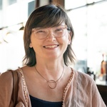 White woman with brown hair, brown eyes and glasses