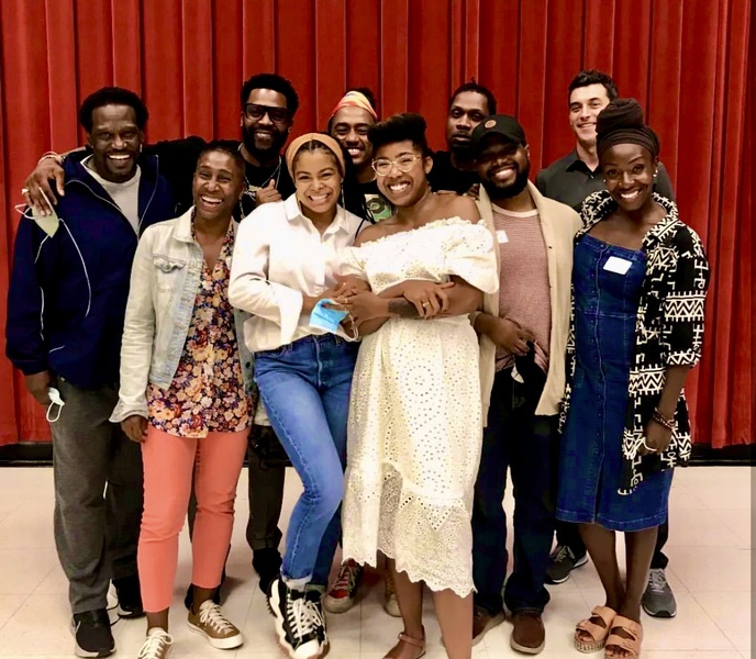  group of ten actors pose in front of red curtain and smile directly at the camera 