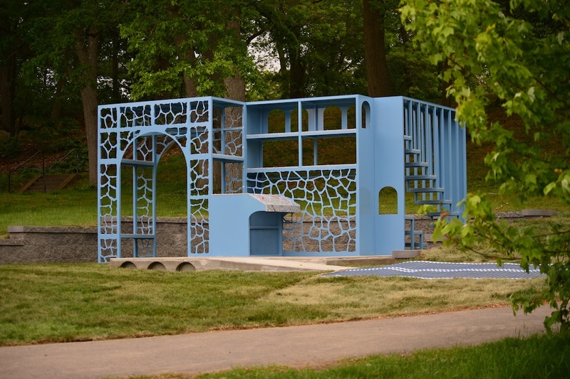  A blue iron sculpture sits outside on a concrete floor. 