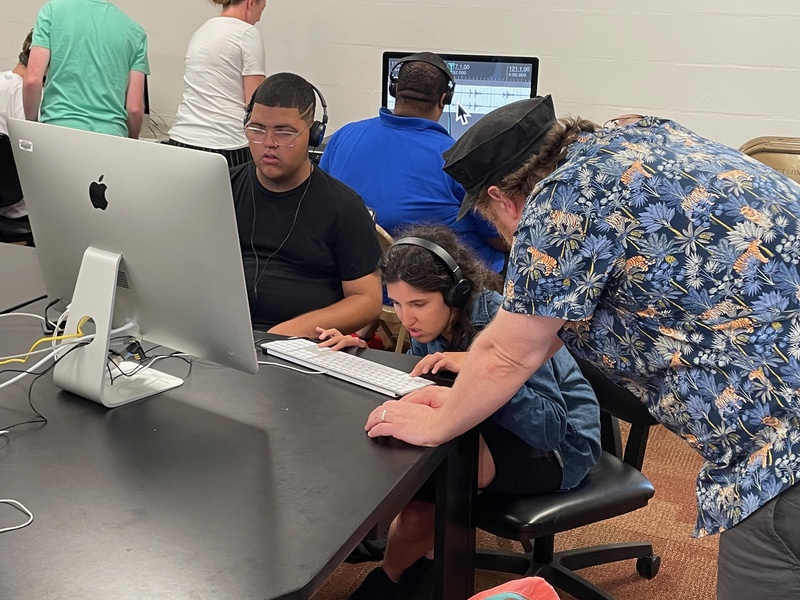  A photo of myself mentoring 2 young blind adults. They sit at a computer workstation editing field recordings they captured at Cape Canaveral Seashore. During the week long camp I worked with a dozen blind young adults to produce sound pieces recorded at 