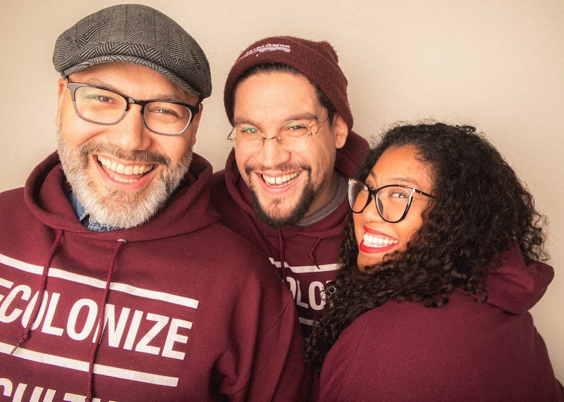  Three individuals smile at the camera. They are all wearing maroon colored sweatshirts. 