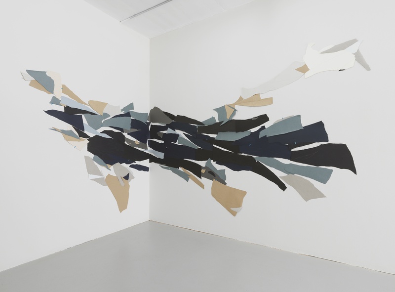  A wall-sized, abstract, collage composed with cut paper shapes. 